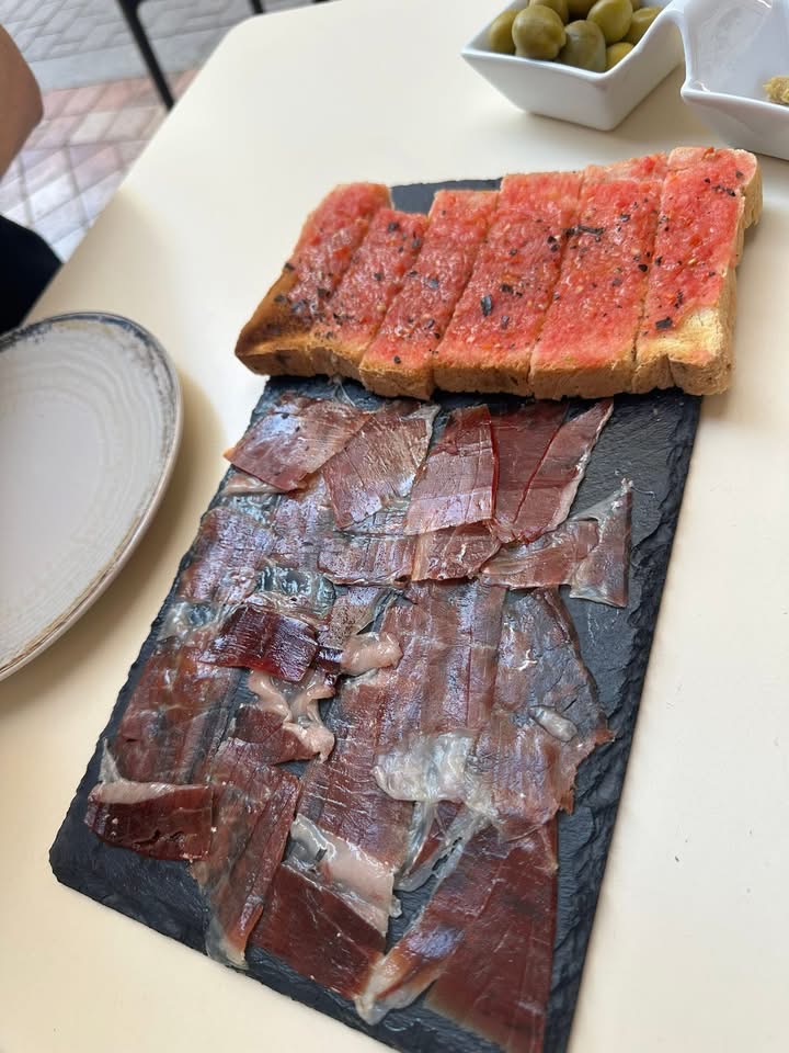 Ein Brett mit Jamón Serrano und Pan con Tomate, mit Oliven