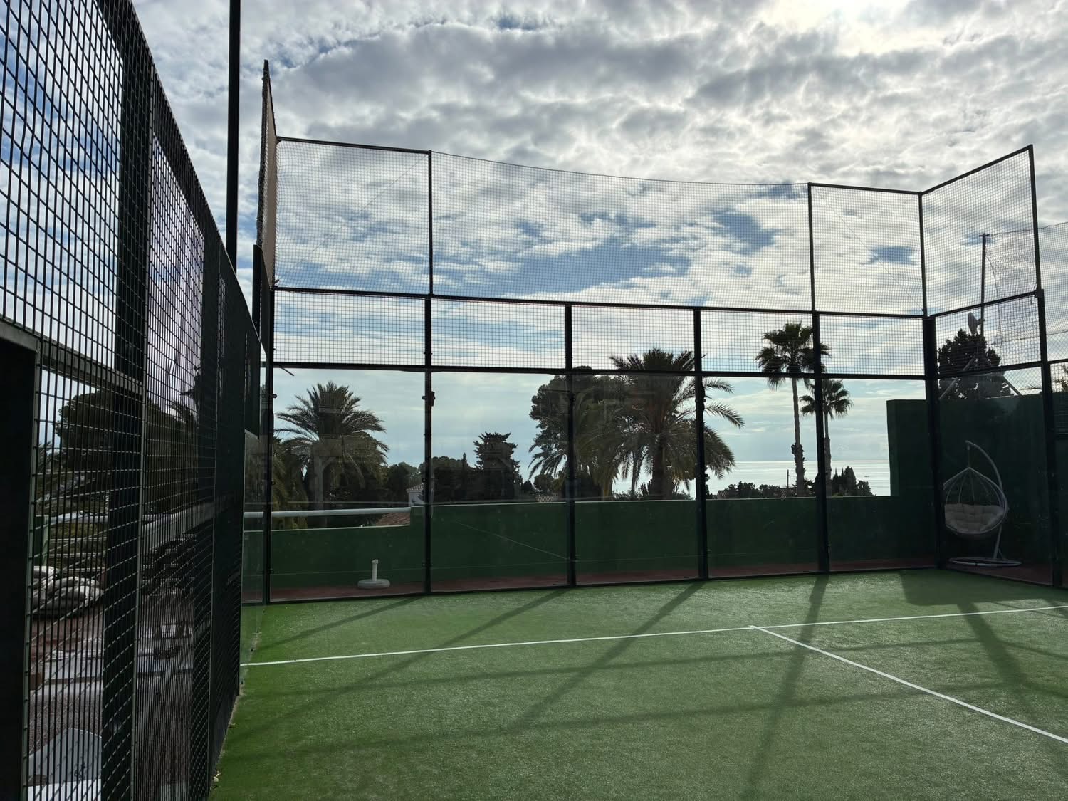 Una pista de pádel con vallas altas y vistas al mar