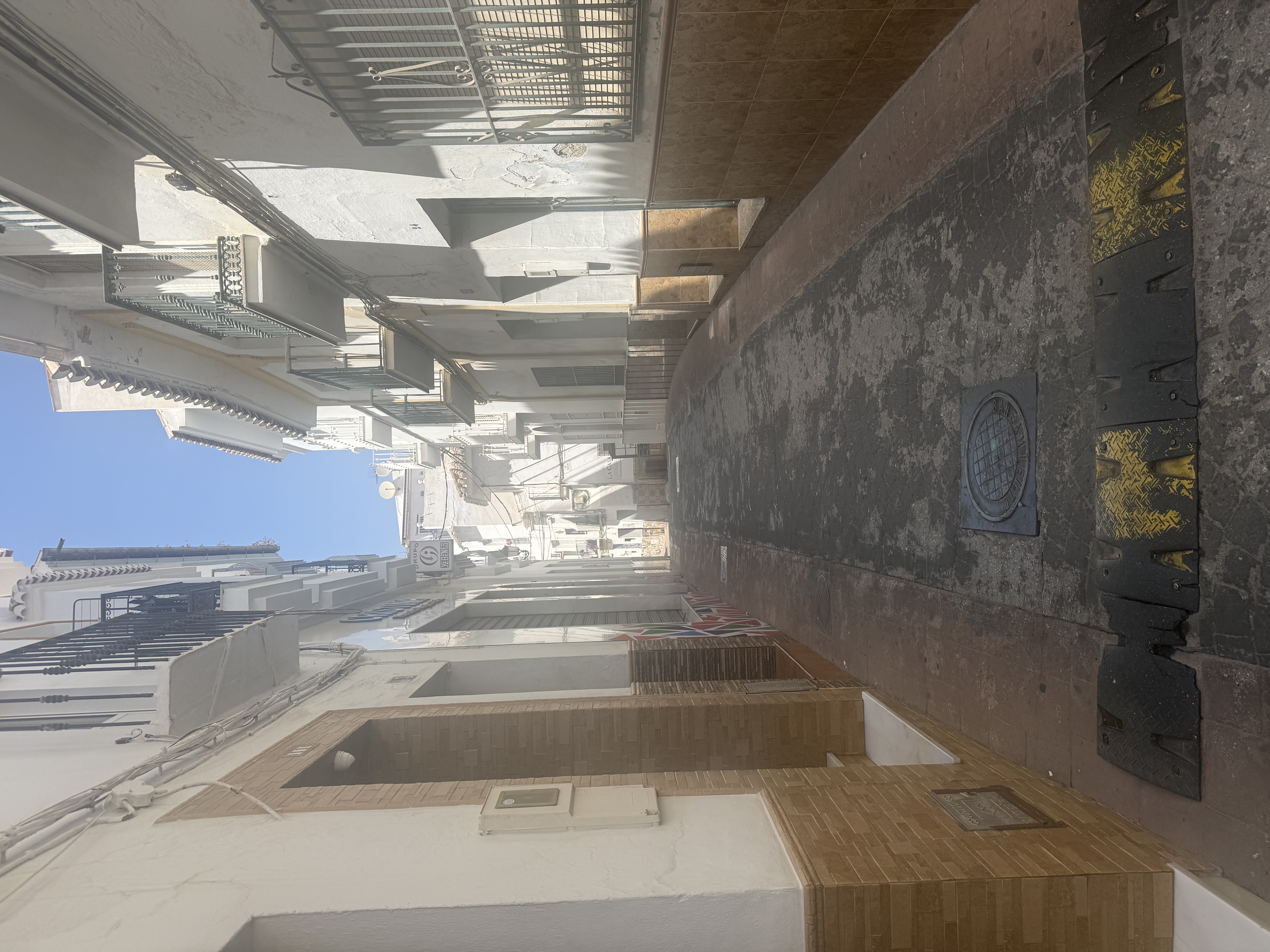 Narrow, sunny street in an Andalusian white village, with