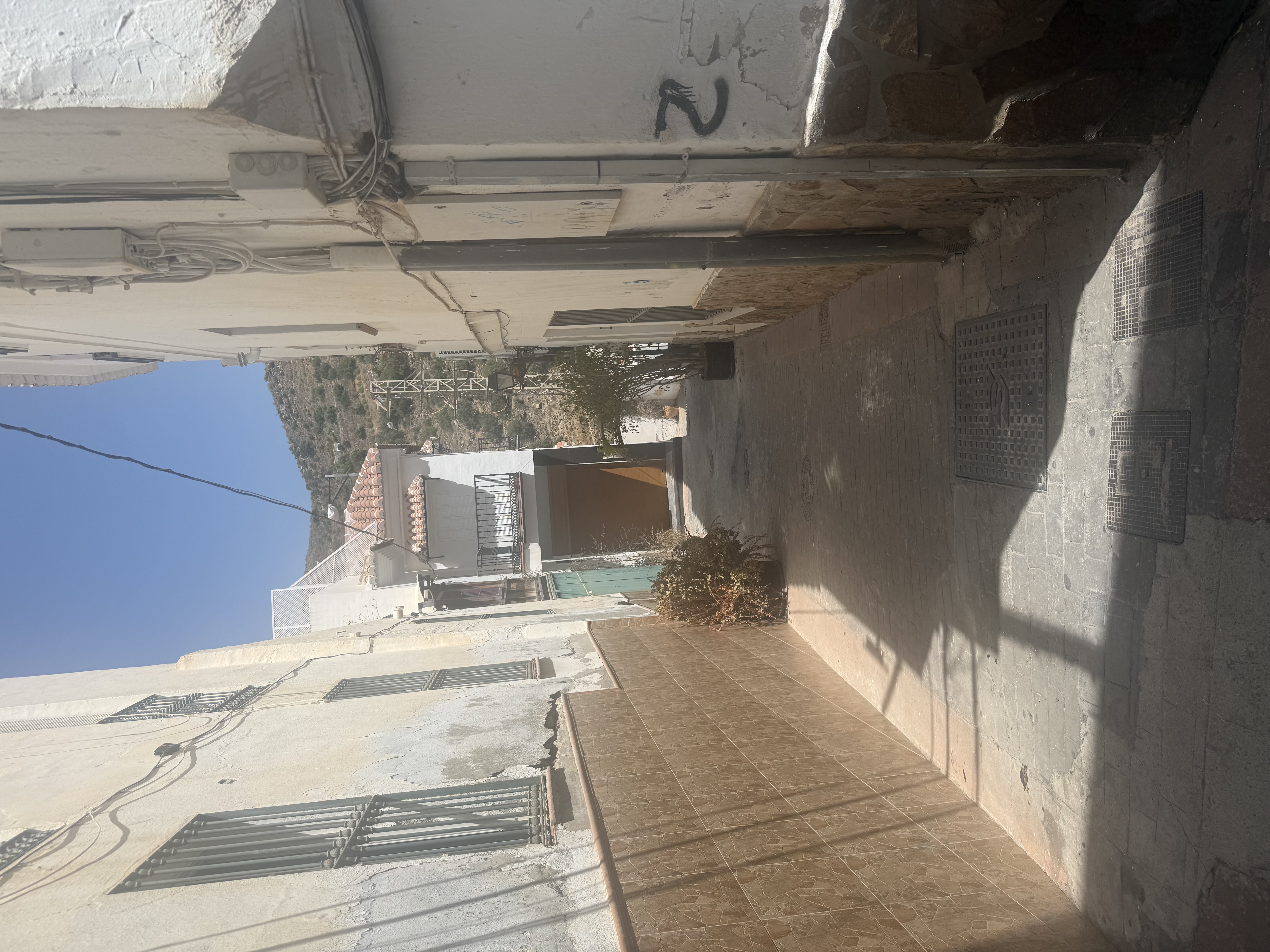 Narrow, shaded street with white houses and mountain